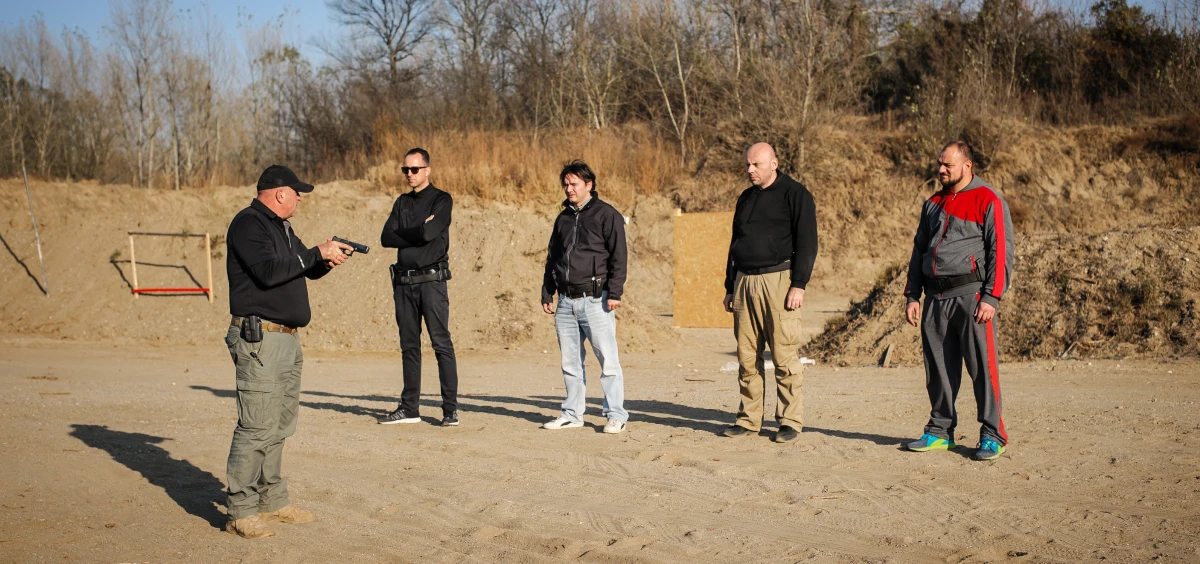 Instructor demonstrating handgun to four men.