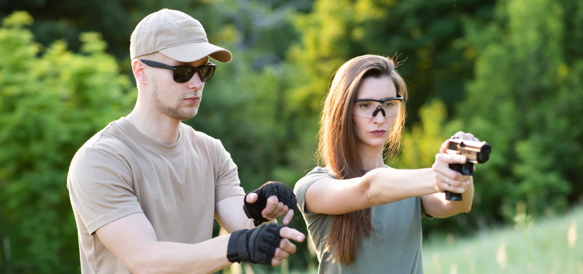 Man instructing woman in shooting outdoors.